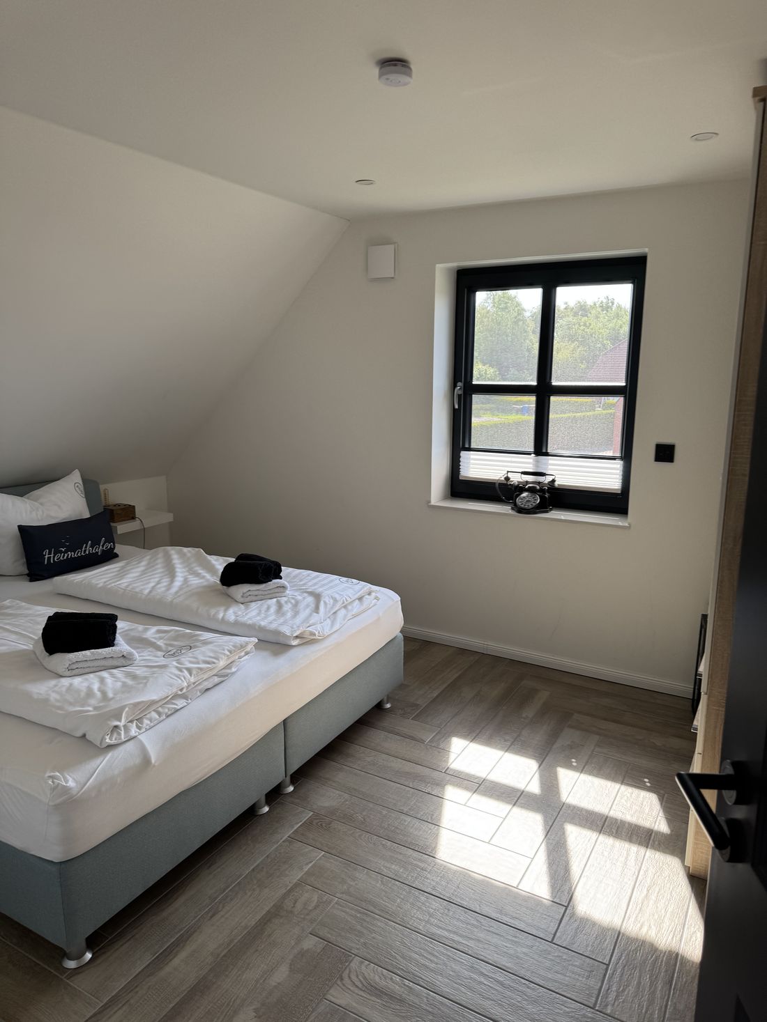 Helles Schlafzimmer mit Doppelbett und Sprossenfenster mit Blick ins Grüne
